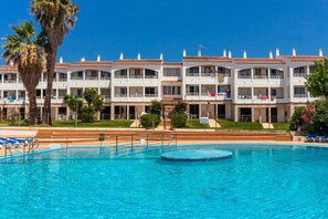 Un hôtel doté d’une piscine, de plusieurs balcons et de palmiers.