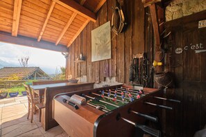 A wooden interior with a foosball table, rustic decor, and a view of the outdoors. - Holiday Home 'Saint Vincent De Mercuze Casavilla' with Mountain View, Private Pool and Wi-Fi (Saint-Vincent-de-Mercuze)