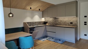 Una cucina moderna con soffitto in legno, mobili a incasso, zona pranzo con tavolo e sedie e una piccola isola con lavello.