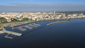 An aerial view of a coastal town with a marina, buildings, and a lighthouse.