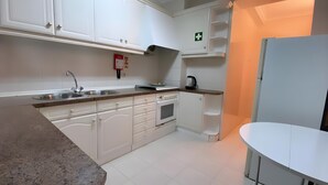 A kitchen with white cabinets, a stainless steel sink, an oven, and a coffee maker.