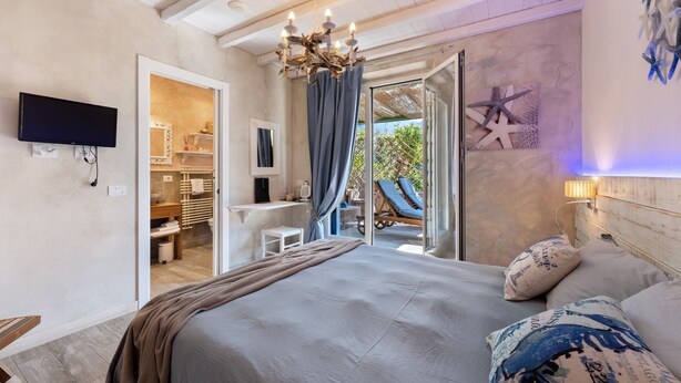 A bedroom with a bed, a TV, a desk, and a view of an outdoor area. - Room 'Stella Marina' with Private Terrace, Wi-Fi and Air Conditioning (Moneglia)