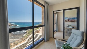 A balcony with a view of the sea and rocky coastline, a chair, and a dining area with a table and chairs. - Vacation 'Maresía' with Sea View, Private Terrace and Wi-Fi (Los Abrigos)