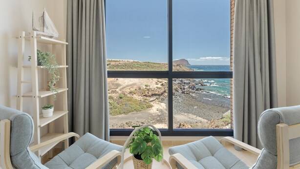 A room with a large window, a plant on a table, and two chairs. - Vacation 'Maresía' with Sea View, Private Terrace and Wi-Fi (Los Abrigos)