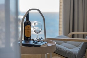 Una bottiglia di vino, un bicchiere da vino e un paio di occhiali su un tavolo con vista sull'oceano.