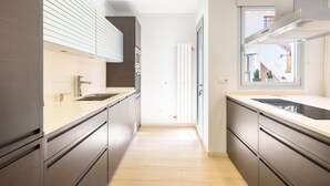 Una cucina moderna con mobili scuri, un piano di lavoro chiaro e una finestra che lascia entrare la luce naturale.