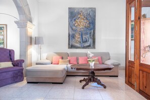 Una sala de estar con sofá, reposapiés y una mesa redonda con un jarrón.