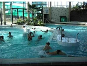 An indoor swimming pool with multiple lanes and a central water feature. - Holiday Home 'Jardin Proche Paris' with Private Garden, Wi-Fi and Air Conditioning (Sainte-Geneviève-des-Bois)