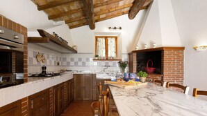 A kitchen with a marble countertop, wooden cabinets, and a brick fireplace. - Holiday Home 'Toscana' with Shared Pool, Private Garden and Wi-Fi (Colle di Val d'Elsa)