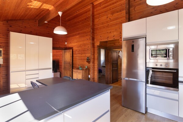 A modern kitchen with wooden walls, stainless steel appliances, and a central island.