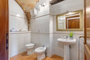 A bathroom with a toilet, bidet, and sink, with a mirror and towel rack. - Cottage 'Rustico Toscano' with Shared Pool, Shared Garden and Wi-Fi (Colle di Val d'Elsa)