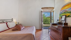 A bedroom with a bed, dresser, and a view of the outdoors.