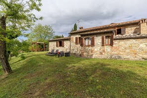 A stone building with a garden area, outdoor seating, and a pergola. - Villa 'Con Piscina E Recinto' with Shared Pool and Private Garden (Colle di Val d'Elsa)