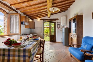 A kitchen with a dining table set for two, wooden cabinets, and a blue armchair. - Villa 'Con Piscina E Recinto' with Shared Pool and Private Garden (Colle di Val d'Elsa)