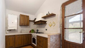 Een keuken met houten kastjes, een fornuis en een metselwerk muur.
