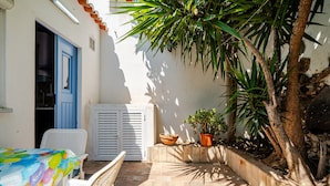 Un patio con una mesa, sillas, una planta en maceta y una puerta blanca.