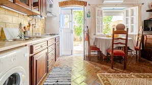 Una cocina con armarios de madera, lavadora y comedor con mesa y sillas.