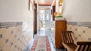 Un pasillo con baldosas estampadas, un banco de madera, un aparador con espejo y una alfombra.