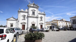 Un edificio histórico con una torre central, un patio con coches aparcados y arquitectura tradicional.