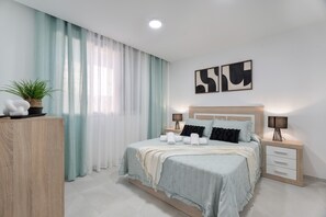 A modern bedroom with a bed, bedside tables, curtains, and wall art. - Vacation 'Iris Tropical' with Mountain View and Wi-Fi (Igueste de Candelaria)