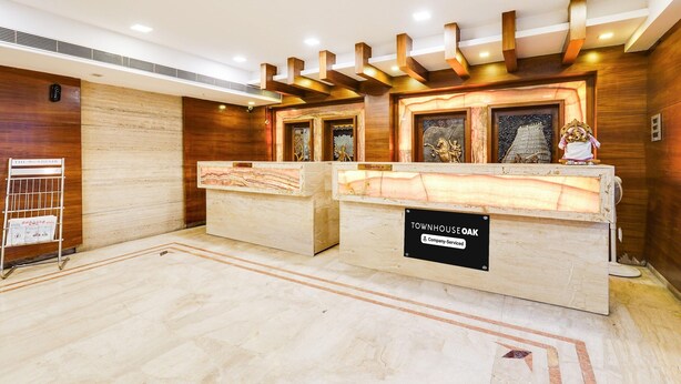 A reception area with two wooden reception desks, a sign indicating 'Townhouse Oak', and a small statue on the right desk. - Luxury Urban Stays Near Chennai Airport (Chennai)