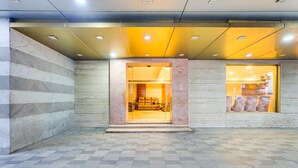 A hotel entrance with a checkered floor, a stone wall, and a glass door leading inside. - Luxury Urban Stays Near Chennai Airport (Chennai)