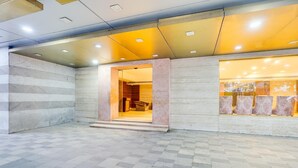 A spacious lobby with a checkered floor, a marble wall, and a glass storefront with patterned curtains. - Luxury Urban Stays Near Chennai Airport (Chennai)