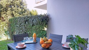 A table set outdoors with a beverage, fruits, and a basket of bread. - Les Jardins d'Aunis by Interhome (Royan)
