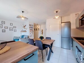 A modern kitchen with a built-in refrigerator, wooden dining table, and chairs. - Les Jardins d'Aunis by Interhome (Royan)