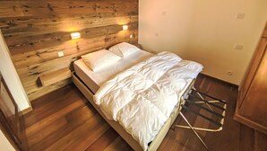 Ein Schlafzimmer mit hölzernem Kopfteil, einem Einzelbett mit weißer Bettwäsche und zwei Wandlampen.