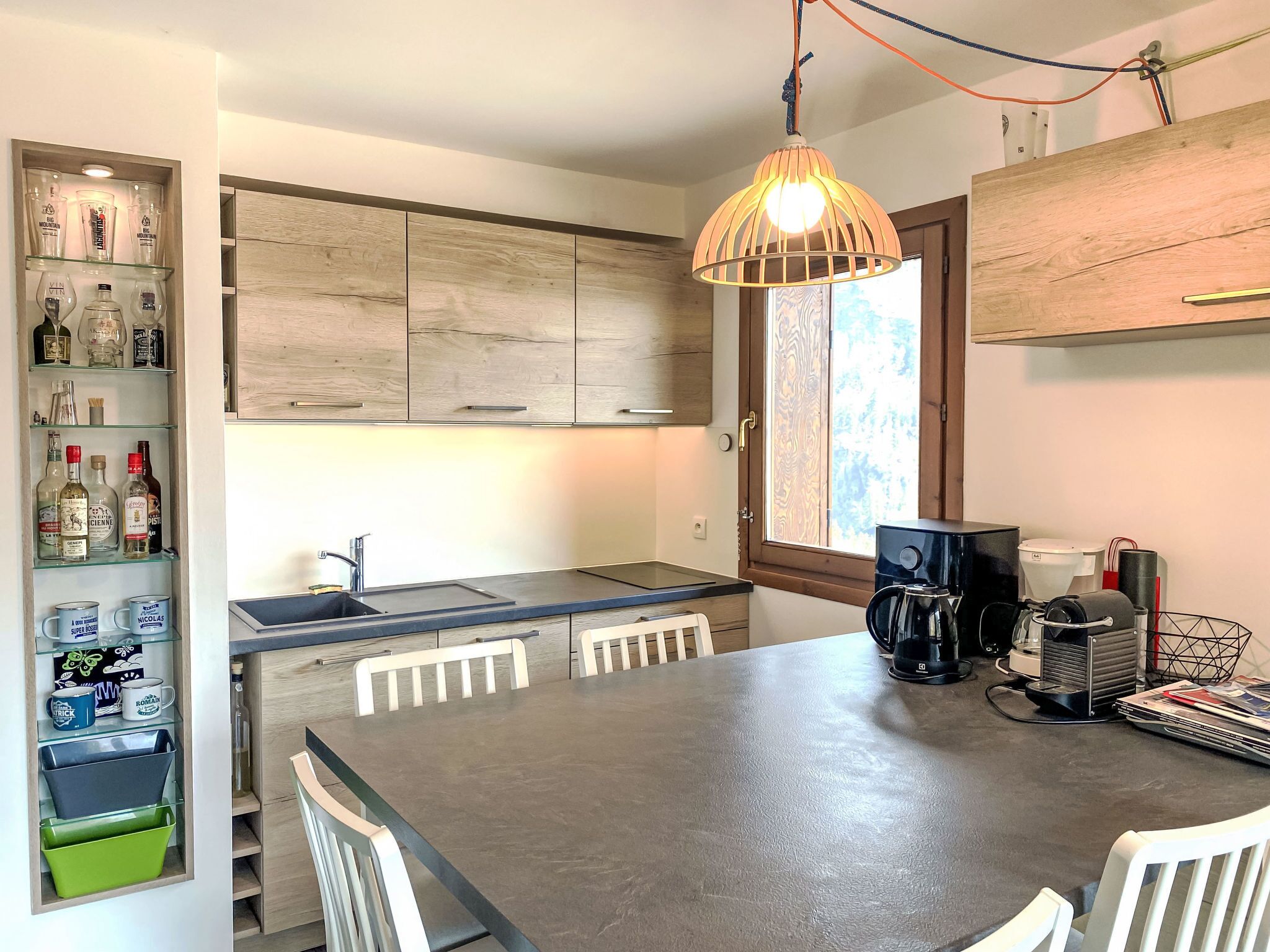 A modern kitchen with wooden cabinets, a built-in sink, and a dining area with a large table and chairs.