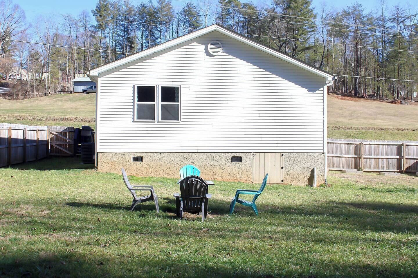A single-story house with a gabled roof, a front porch with two chairs, and a small attached garage.