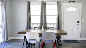 A dining area with a wooden table, two white chairs, and a red chair. - Ventures in Leicester (Leicester)