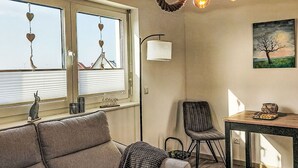 Ein Zimmer mit einer Couch, einem Tisch, einem Stuhl, einer Lampe und einem Gemälde an der Wand.