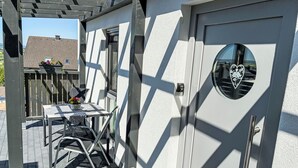 Ein modernes Gebäude mit weißer Fassade und einer Tür mit einem herzförmigen Fenster.