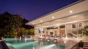 Et moderne hotel med en stor udendørs pool, liggestole og en trappe op til de øvre etager.