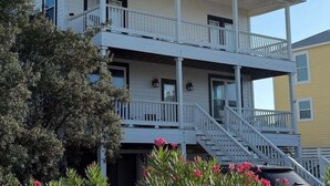 A two-story building with a balcony and a staircase leading to the upper floor. - Pet Friendly- Fort Morgan | Sleeps 12 | 3BR | 2.5BA (Gulf Shores)