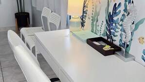 A modern room with a white desk, chairs, a TV, and a wall mural.