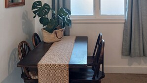 A dining area with a dark wooden table, a woven placemat, and a potted plant. - European Apartment in New Plymouth Central (New Plymouth)