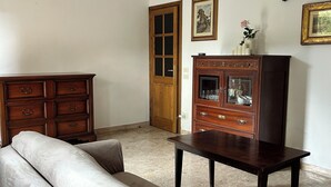 Una sala de estar con un sofá color beige, un aparador de madera y una mesita.