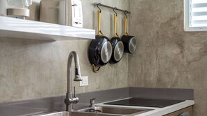 A kitchen with a double sink, stainless steel faucet, and a countertop. There are three hanging pots on a rack above the sink. - Luquillo Family Home | Sleeps 10 | Near Beach (Juan Martín)