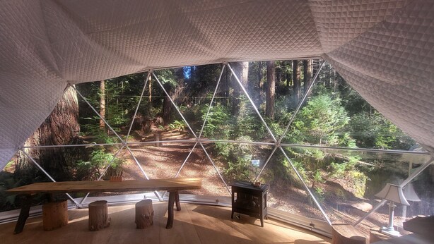 A tent with a wooden floor, a bench, and a small table. - Fieldbrook Gnome Dome (McKinleyville)