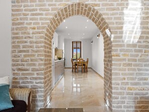 A hallway with a brick archway leading to a dining area with a table and chairs. - Apartment in Vodnjan With Pool & Jacuzzi (Vodnjan)