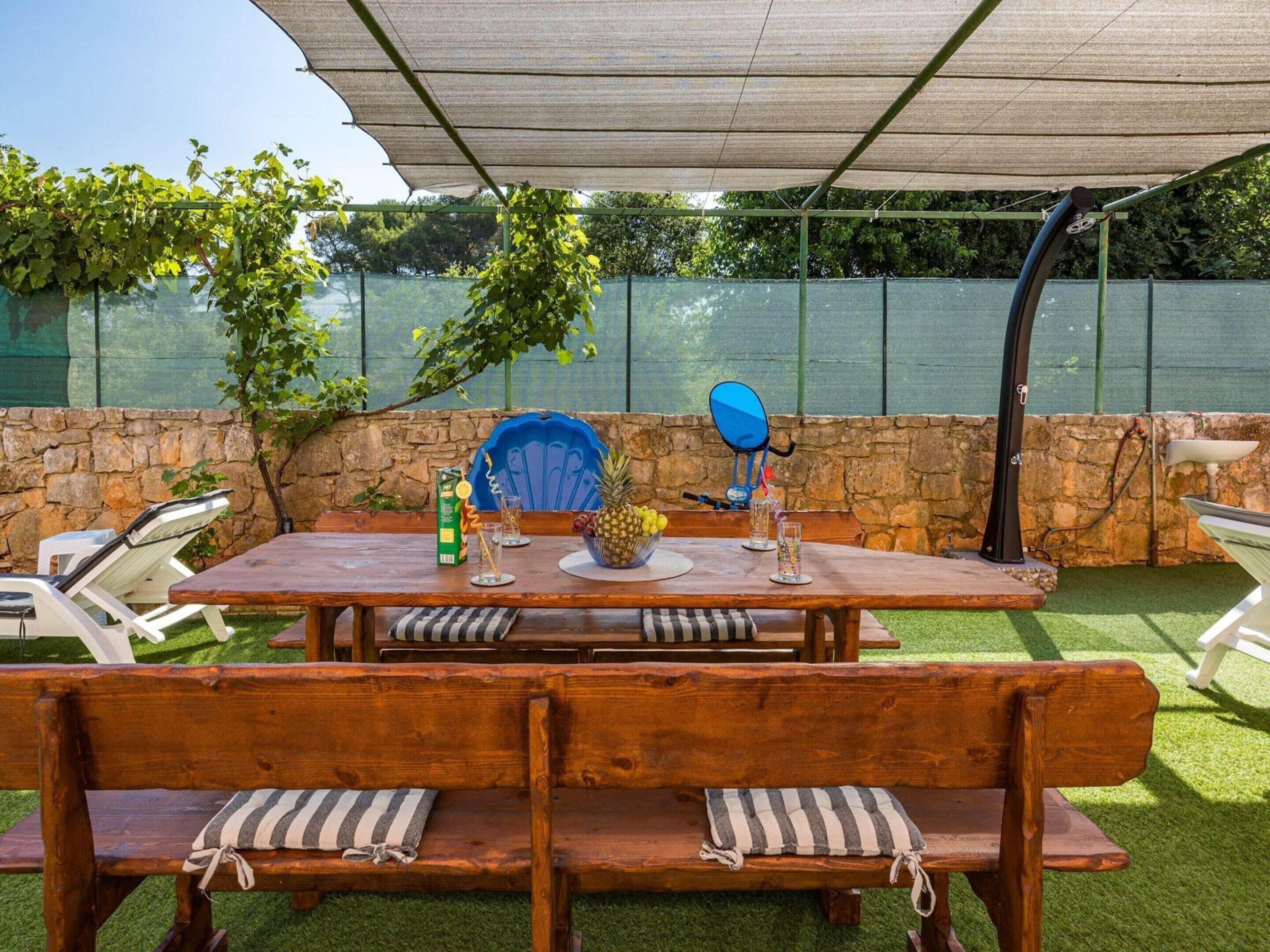 Un patio al aire libre con una mesa de madera, bancos y una silla azul.