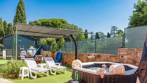 A backyard with a hot tub, lounge chairs, a covered patio, and a stone wall. - Apartment in Vodnjan With Pool & Jacuzzi (Vodnjan)