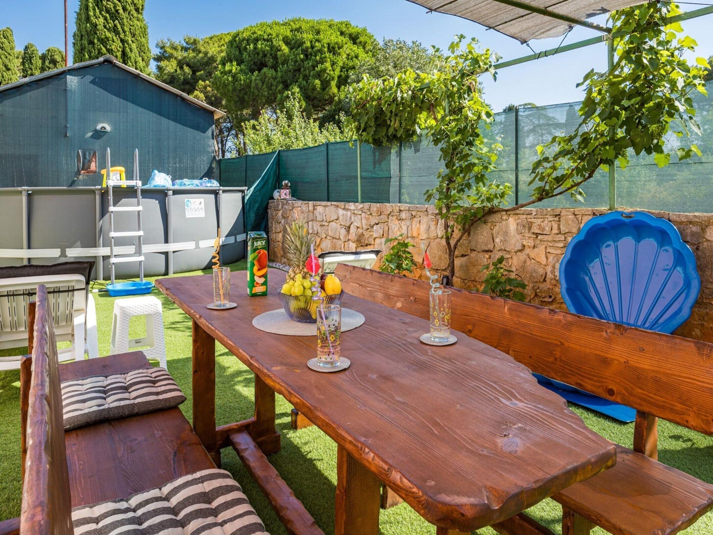 Een terras buiten met een houten eettafel, omringd door een stenen muur en een blauwe stoel.