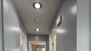 Un pasillo con paredes grises, suelo de madera y luces empotradas en el techo.