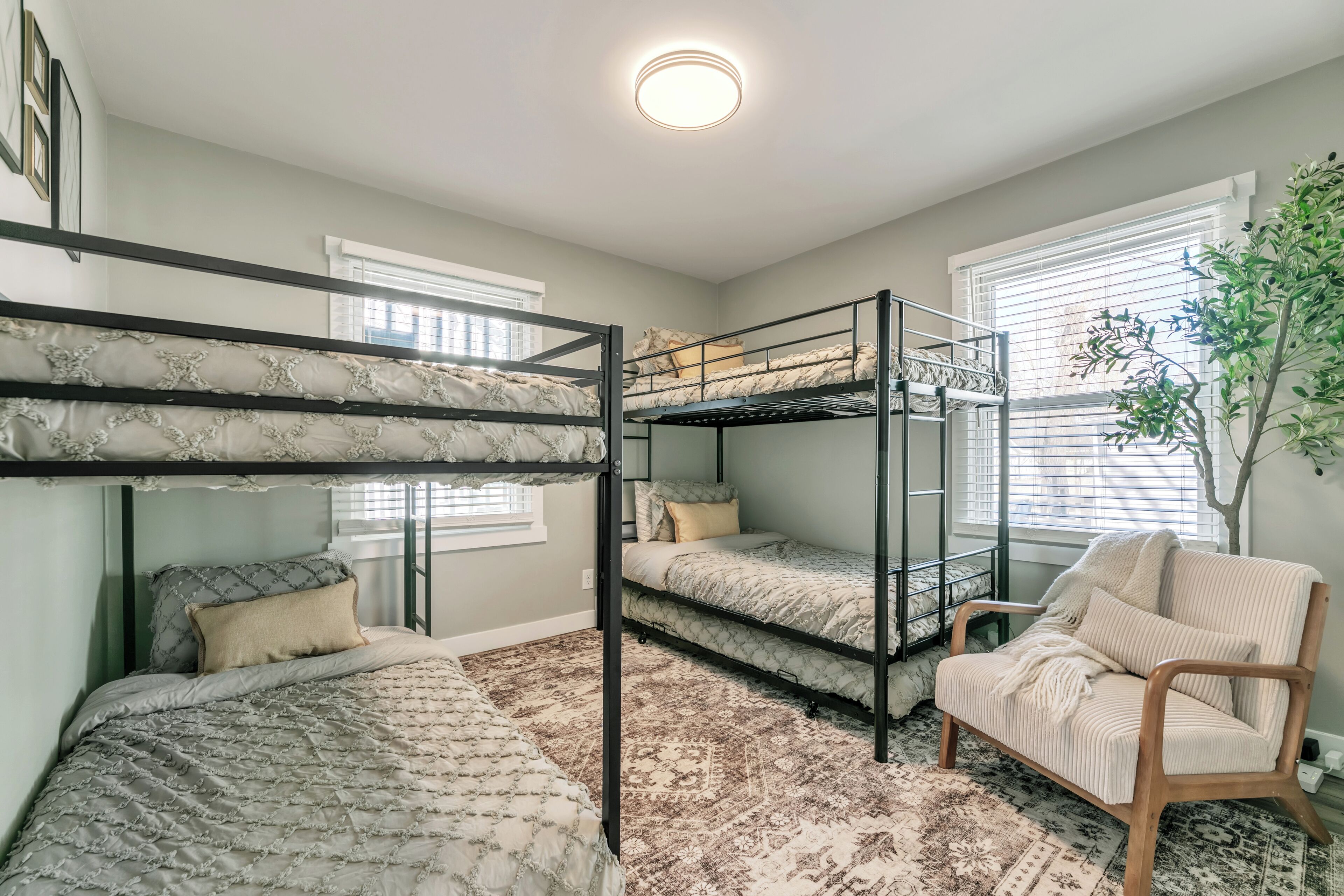Dormitorio con literas, una silla de madera y un ventanal grande.
