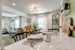 Comedor con una mesa blanca dispuesta para cuatro personas, rodeada de sillas, y un juego de mesa de madera sobre la mesa.