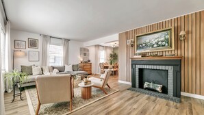 Un salon moderne avec une cheminée, des lambris en bois et un coin repas.